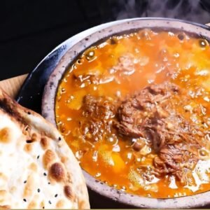 Zartes Rindfleisch in Tomaten-Knoblauch-Soße, serviert im heißen Steintopf mit Hulba