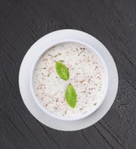 Cremiger Joghurt mit fein gehackten Gurken und frischer Minze - kuhlend und aromatisch."